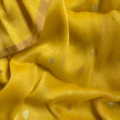 A close-up of draped yellow fabric with subtle metallic gold and silver woven accents, showing its soft texture and folds.