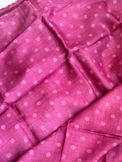 A close-up of a pink fabric blouse matching to pallu, with a repeating light pink polka dot pattern, shown in soft folds.